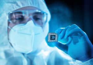 Close-up view of a technician holding a high-performance microprocessor in a controlled lab environment, illustrating innovation in embedded hardware design.